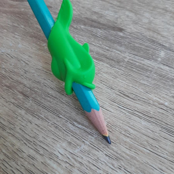 Guide doigt poisson vert fixé sur un crayon, aidant l’enfant à adopter une posture correcte pour écrire